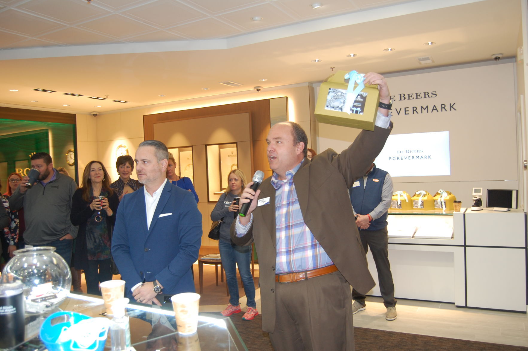 Jack Lewis Jewelers President & CEO John Carter, McLean County Chamber of Commerce President & CEO Charlie Moore holding up a box of pine cones